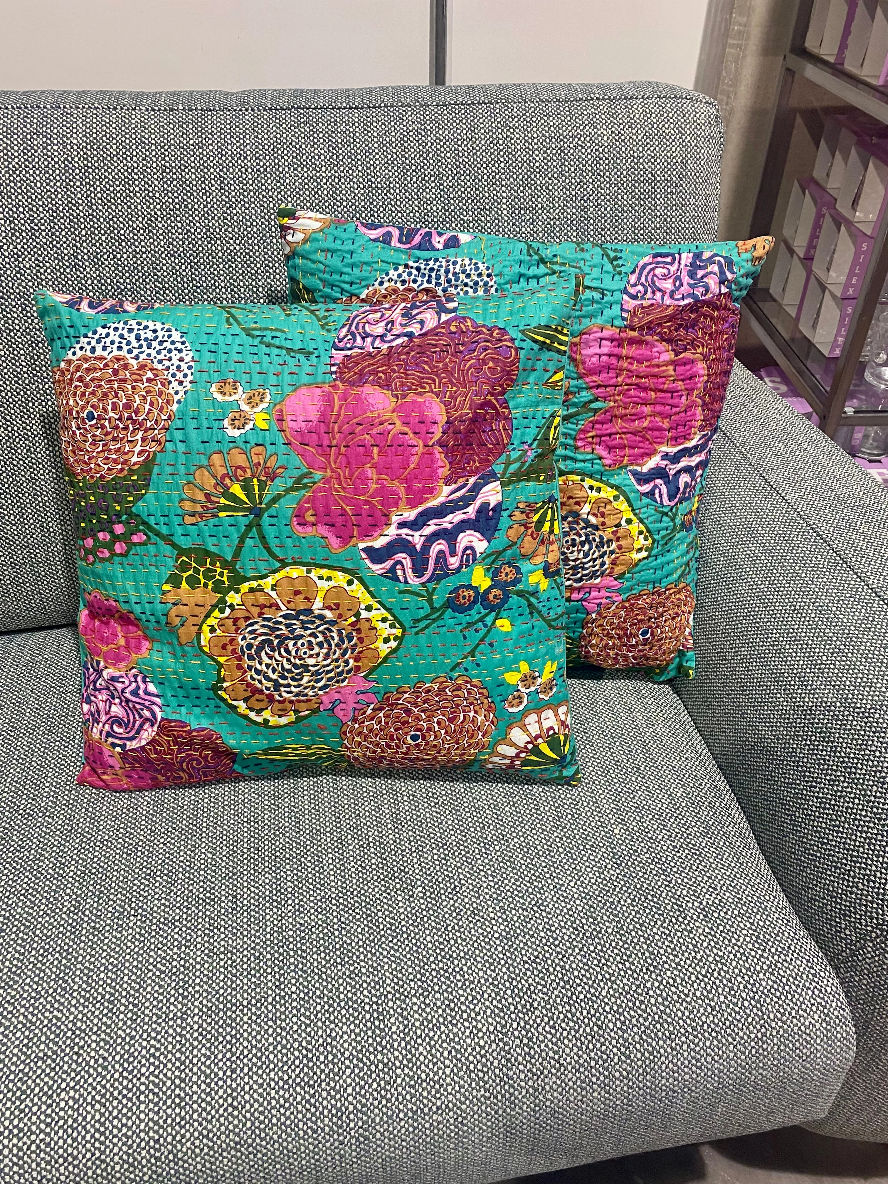 Cojín estampado de flores con pespuntes.